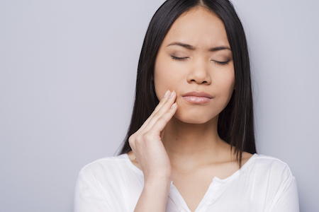 woman holding her mouth from tooth pain in need of an emergency dentist in Richmond, VA