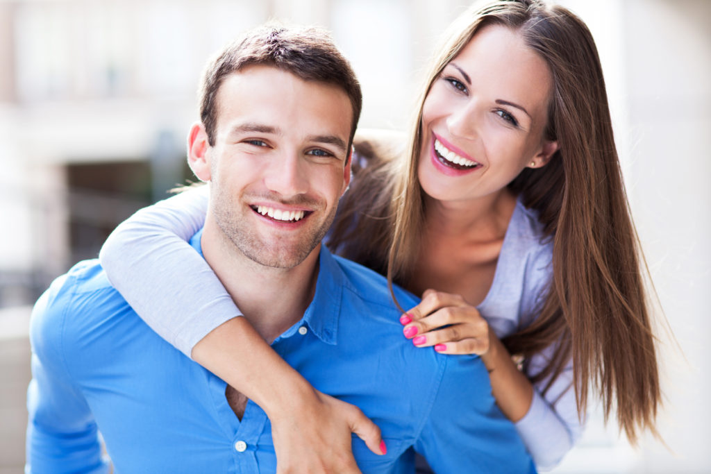 A couple show off their teeth after a cosmetic dentistry teeth whitening treatment in Richmond, VA.