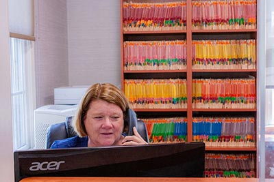 Front desk receptionist speaking to patient on the phone about dental insurance